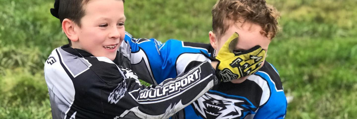 Two boys, laughing wearing wulfsport suits and gloves