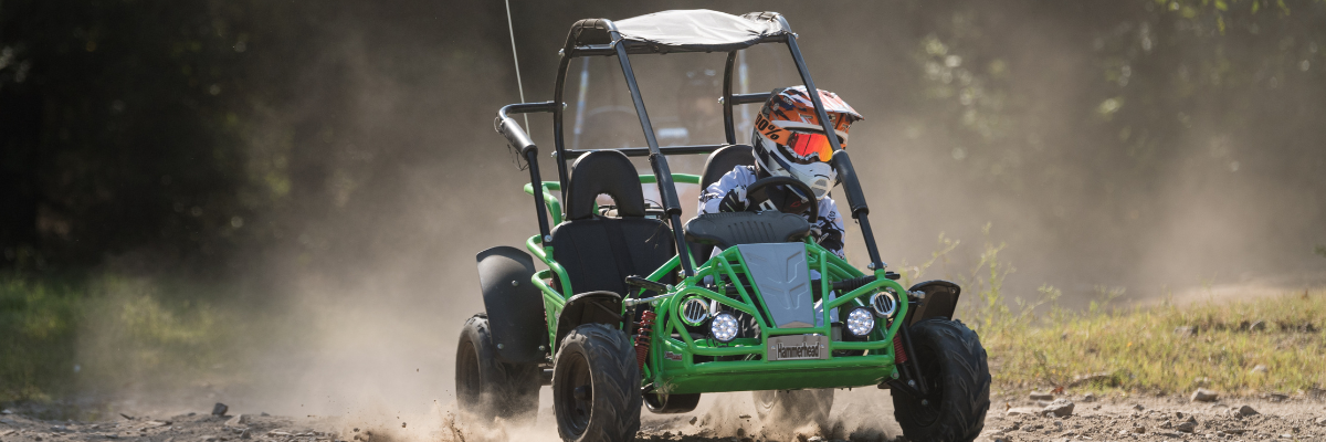 Child riding a green petrol off road buggy on a dirt track