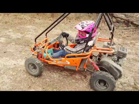 Girl riding a orange off road buggy on a dirt track